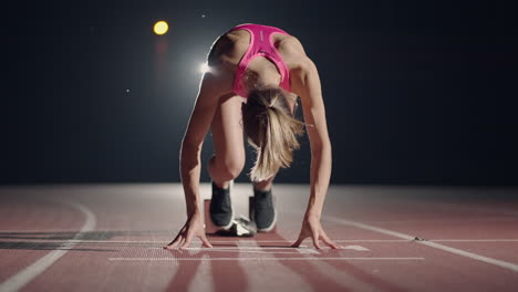 Fitte-Mixed-Race-Athletin-Auf-Einer-Laufstrecke-In-Einem-Outdoor-Sportstadion,-Die-Ein-Rennen-Aus-Den-Startblöcken-In-Zeitlupe-Mit-Hintergrundbeleuchtung-Und-Linseneffekt-Startet.-Nacht